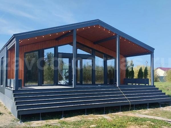 Летний дом с панорамным остеклением торца и террасой на высоких ступенях